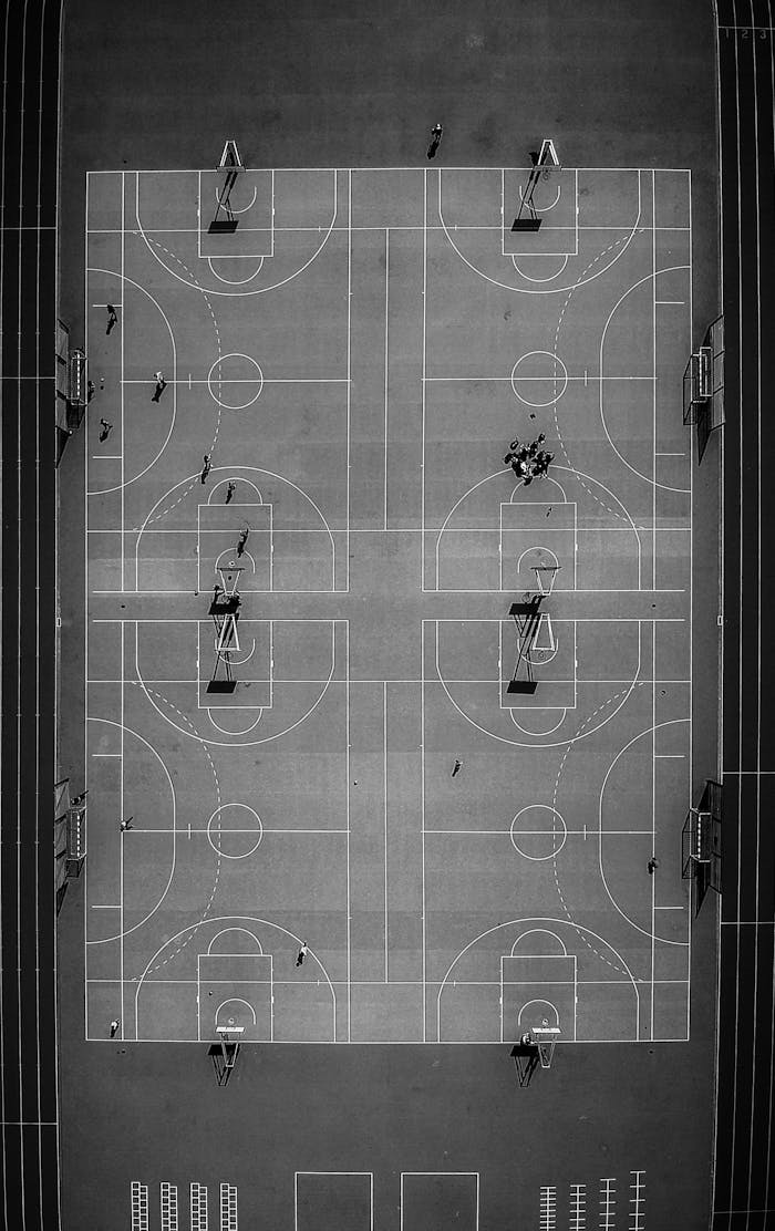 our-services-1 Drone captures a striking black and white aerial view of a basketball court in Chamonix, France, highlighting its symmetry.